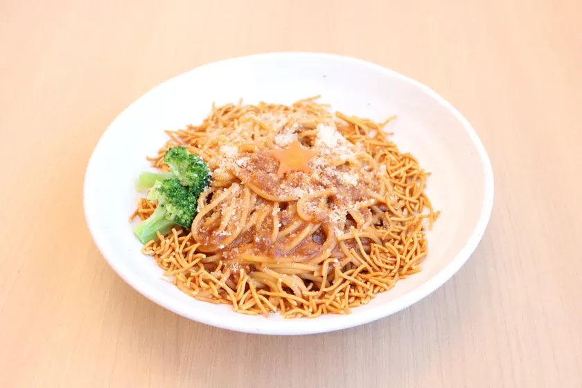 白い器に盛られた、麺料理の写真です。麺の上にはソースがかかっており、星型にカットされた人参、ブロッコリーが添えられています。粉チーズがかかっているのが確認できます。