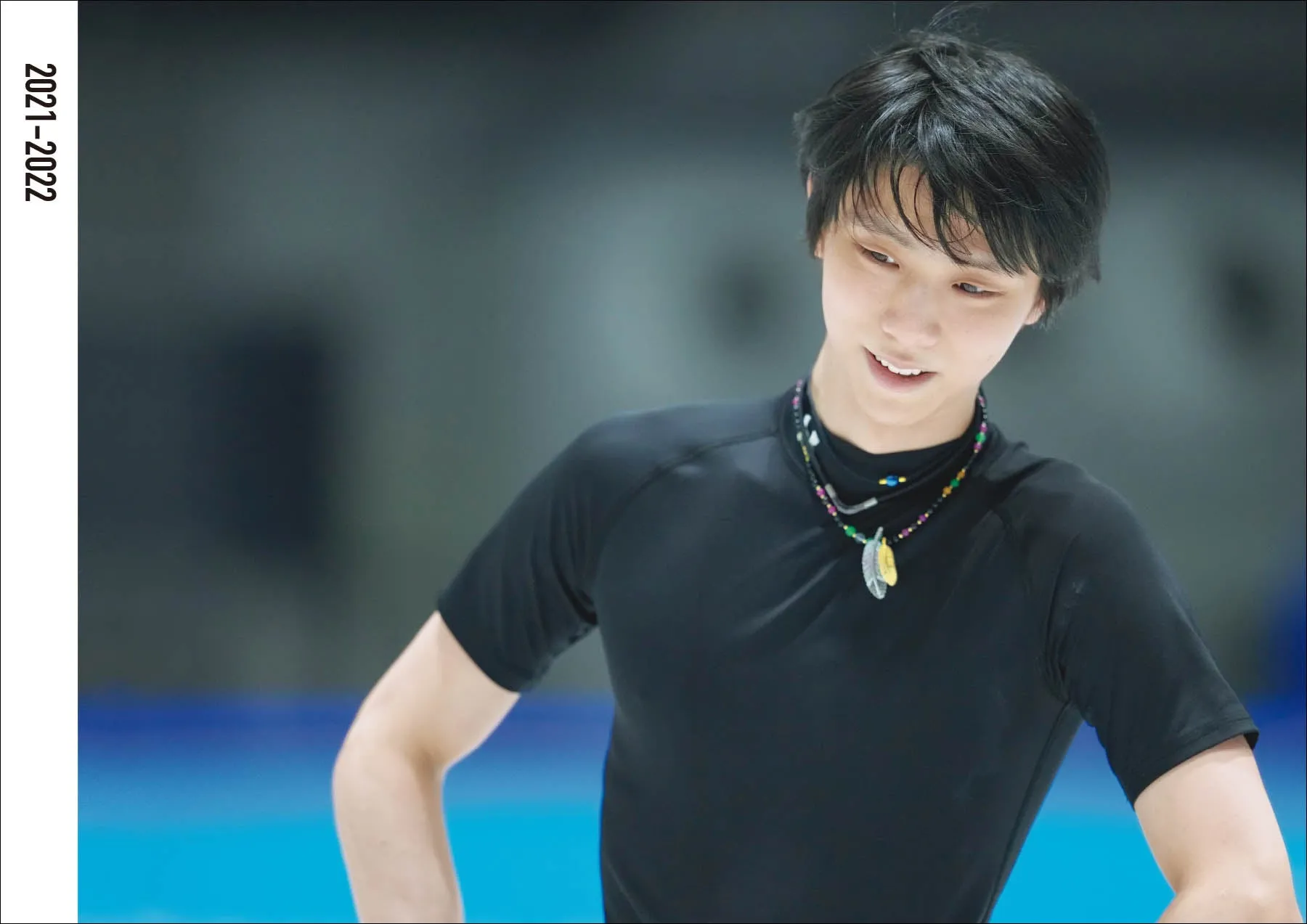 黒いシャツを着た男性が微笑んでいる写真です。背景はぼやけています。
