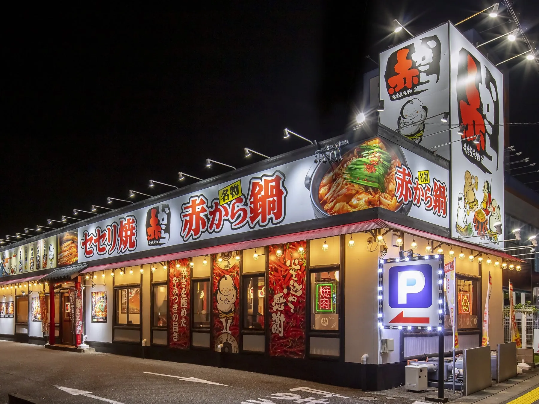 夜の赤から鍋の店の外観。看板には「赤から鍋」と書かれ、店の前には駐車場を示す看板がある。