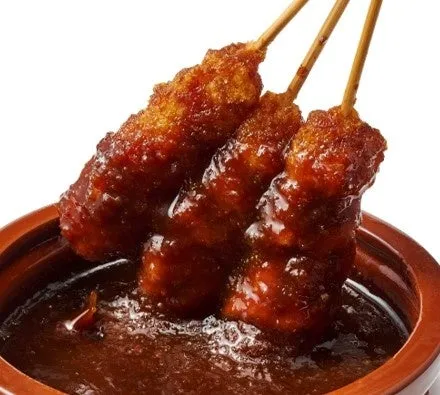 串に刺さった揚げ物料理が、ソースに浸かっている様子。