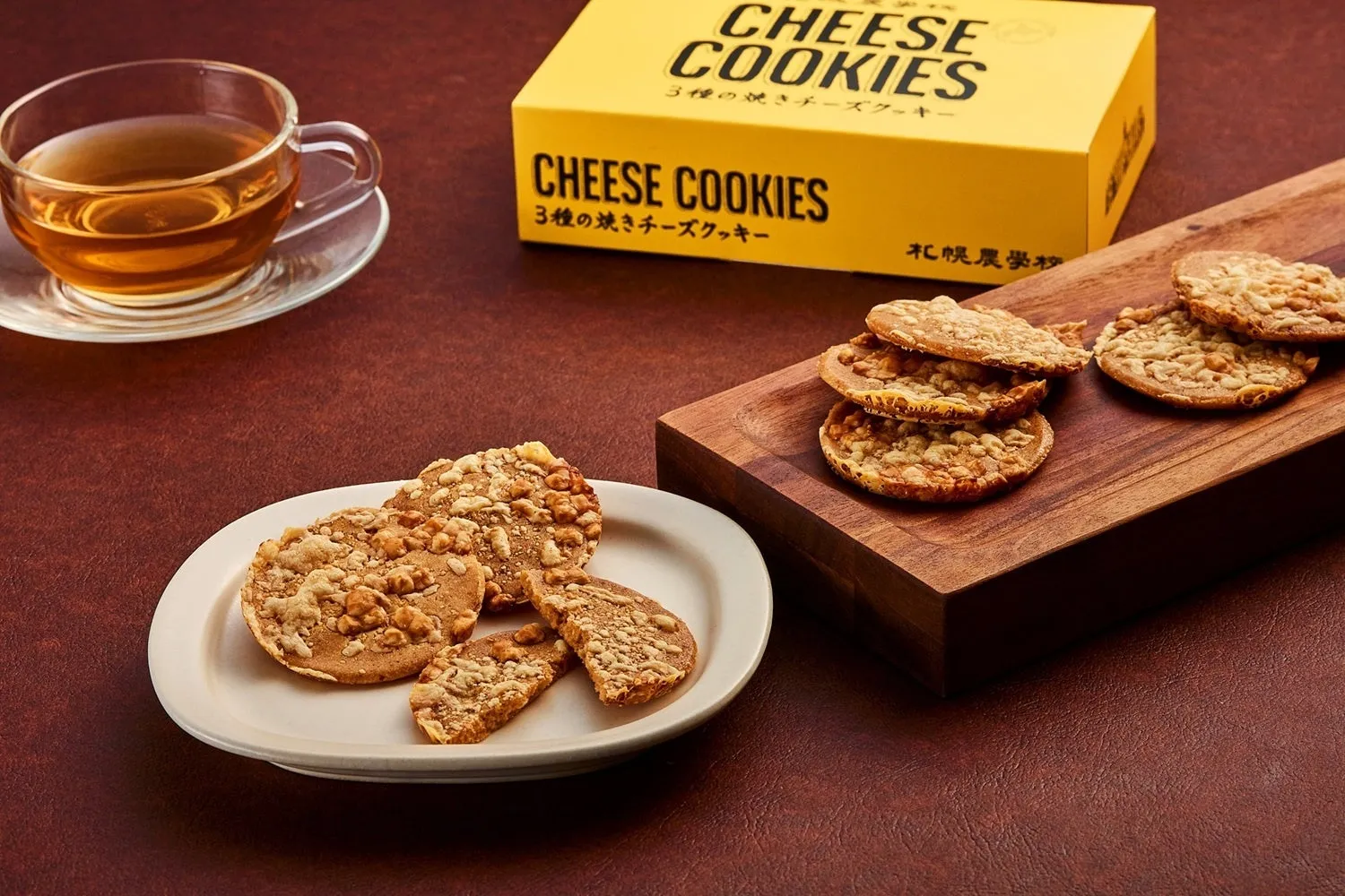 チーズクッキーと飲み物の写真。クッキーは木製のボードと白い皿に盛られており、箱も写っている。