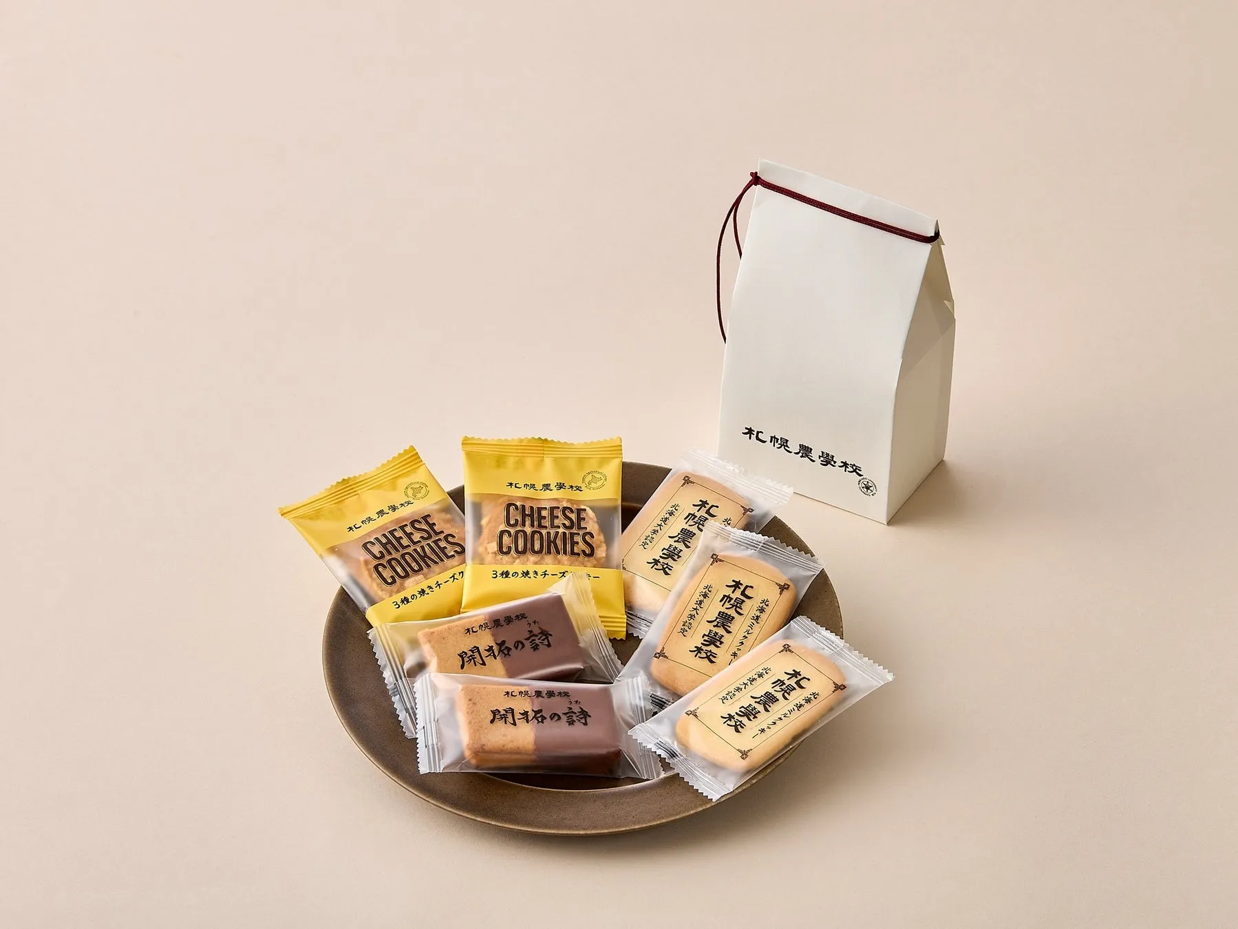お菓子が皿の上に並べられており、白い箱が添えられている写真です。チーズクッキーや開拓の詩という商品名が見えます。