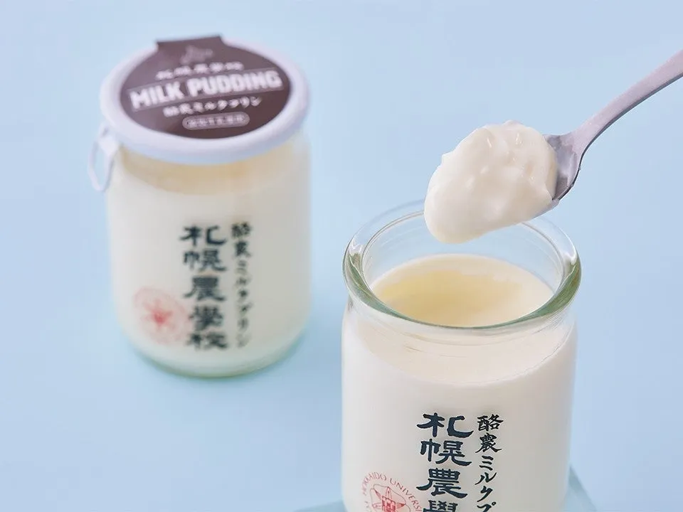 2つのガラス瓶に入ったミルクプリンの写真。スプーンですくって食べようとしている様子。
