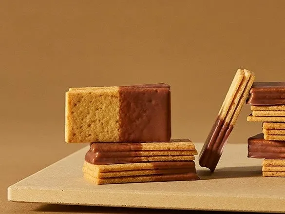 チョコレートがけされたお菓子の写真です。何層にもなったビスケットにチョコレートが半分だけかかっています。チョコレートがけされたビスケットが積み重なっており、一本だけ立てかけられています。