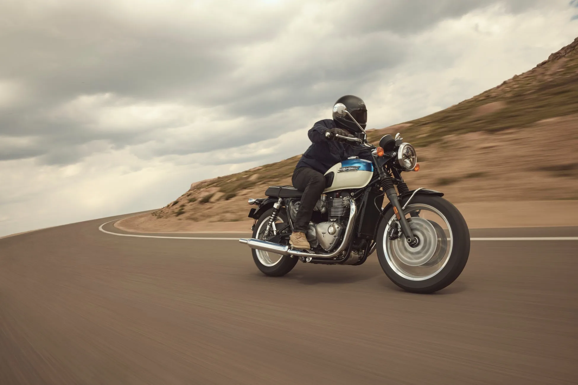 TRIUMPHのバイクに乗ってカーブを走る人