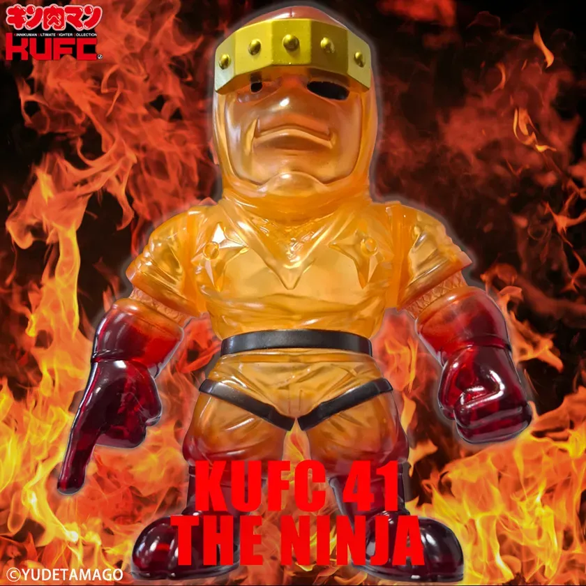 炎を背景に、透明感のあるオレンジ色のボディスーツを着た、キン肉マンのキャラクターのフィギュア。頭には金色の飾りがあり、赤い手袋とブーツを履いている。