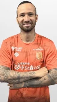 オレンジ色のユニフォームを着た男性のポートレート。彼は腕にタトゥーがあり、笑顔でカメラを見ている。