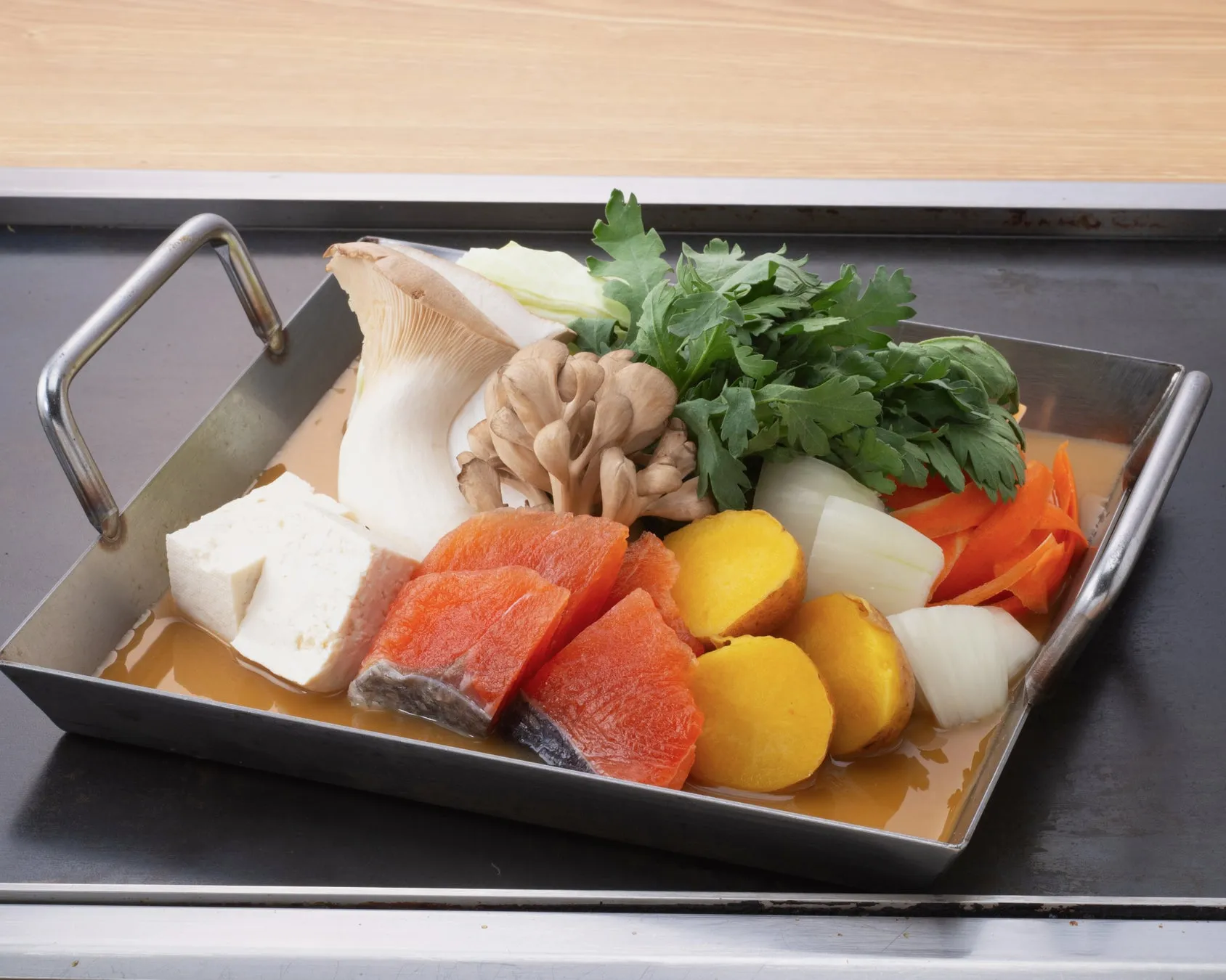 魚、豆腐、野菜などを盛り付けた料理の写真です。鍋料理のように見えます。