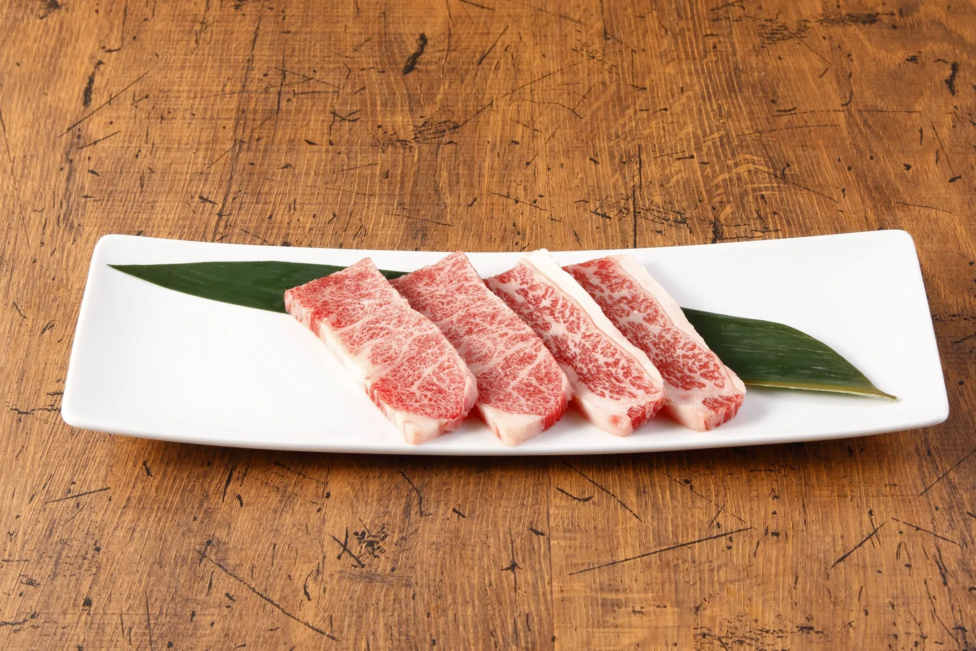 白い皿に盛られた、霜降り肉の塊のクローズアップ。