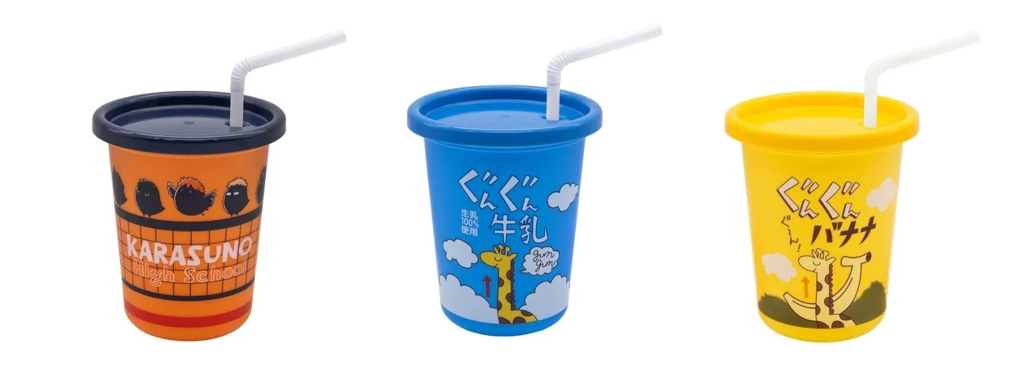 3つのカップが並んだ画像。それぞれ異なるデザインで、オレンジ色のカップには「KARASUNO High School」の文字とキャラクターが描かれています。青色のカップには「ぐんぐん牛乳」の文字とキリンのイラスト、黄色のカップには「ぐんぐんバナナ」の文字とバナナを持ったキリンのイラストが描かれています。すべてのカップにはストローが刺さっています。