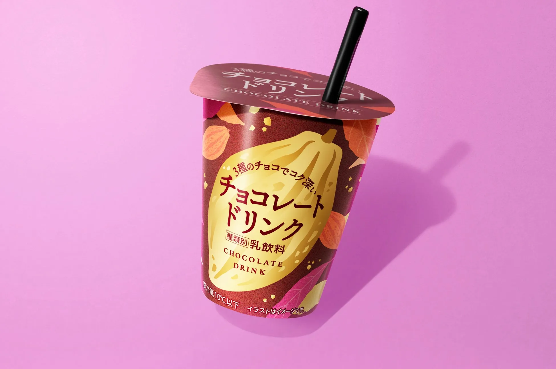 チョコレートドリンクのパッケージの画像です。カップにはチョコレートドリンクの文字や、3種のチョコレートを使用していること、種類別乳飲料であることが記載されています。背景はピンク色です。