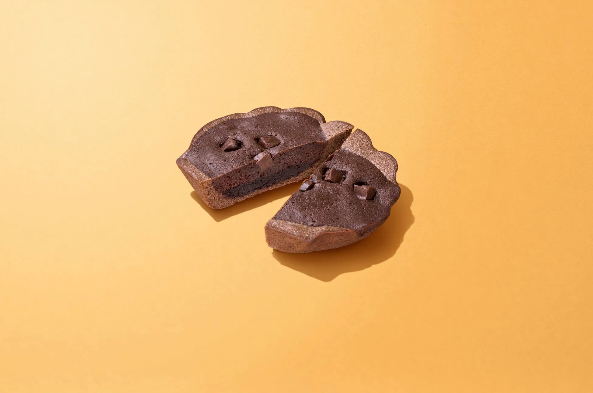 チョコレートケーキが2つに割れて、黄色い背景に置かれています。