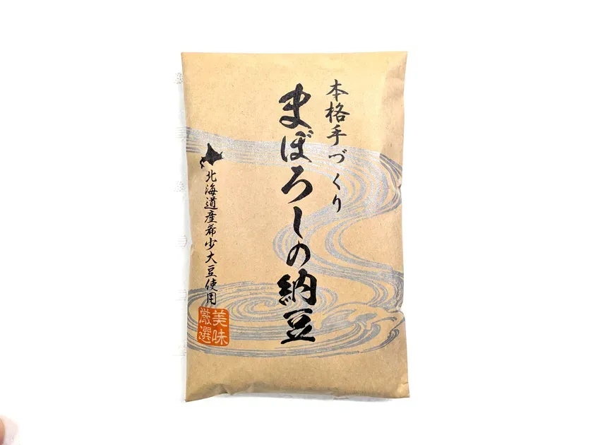 茶色のパッケージに入った納豆の写真です。パッケージには「本格手づくり」「まぼろしの納豆」などの文字が書かれています。