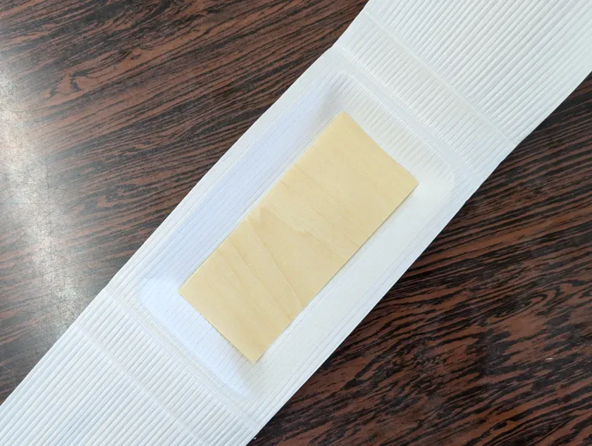 木製の板が白い容器に入っている様子を真上から撮影した写真。背景は木目調のテーブル。