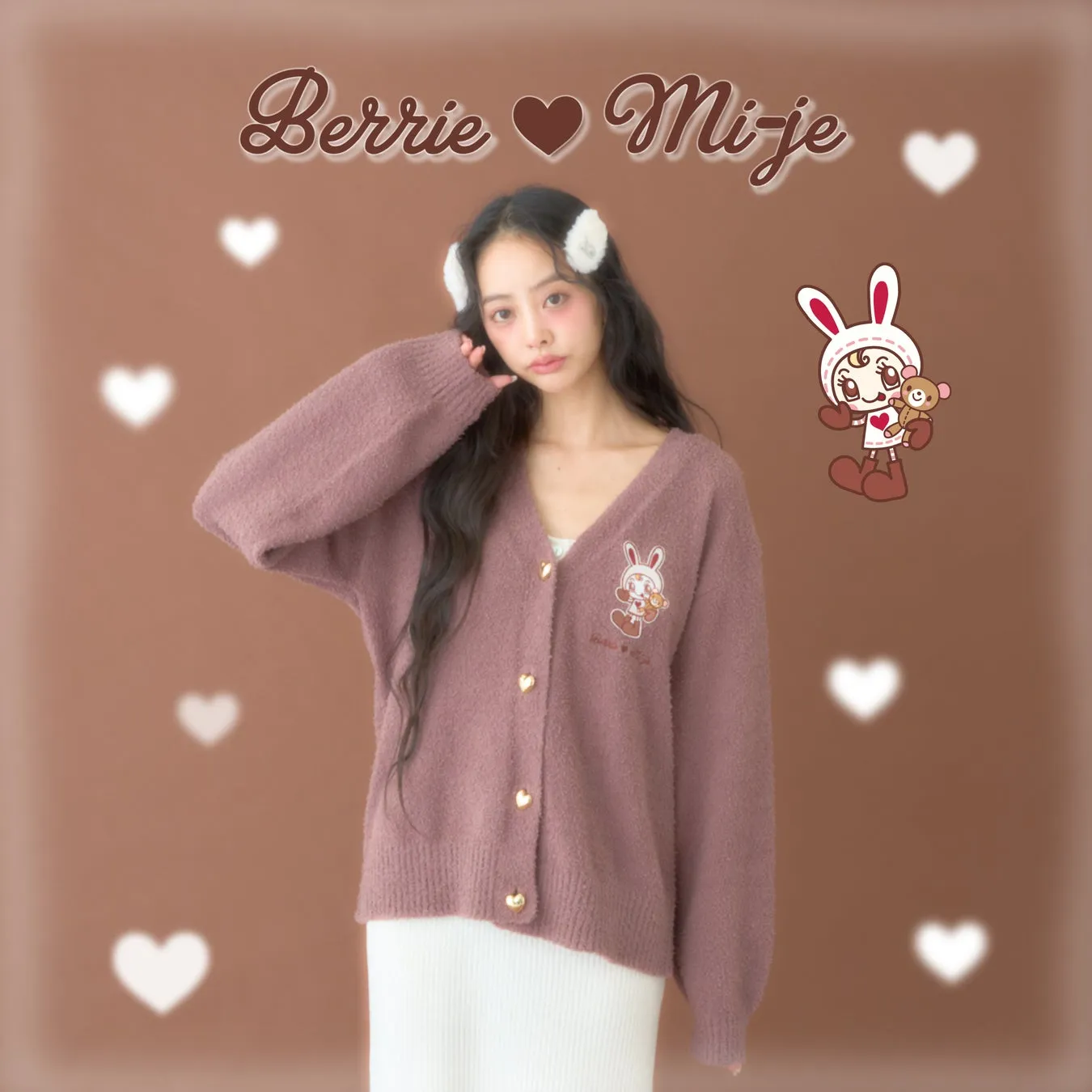 女性がピンク色のカーディガンを着てポーズをとっている写真