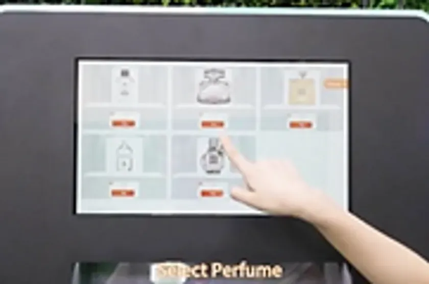 香水を選ぶためのタッチスクリーンディスプレイに触れる手。