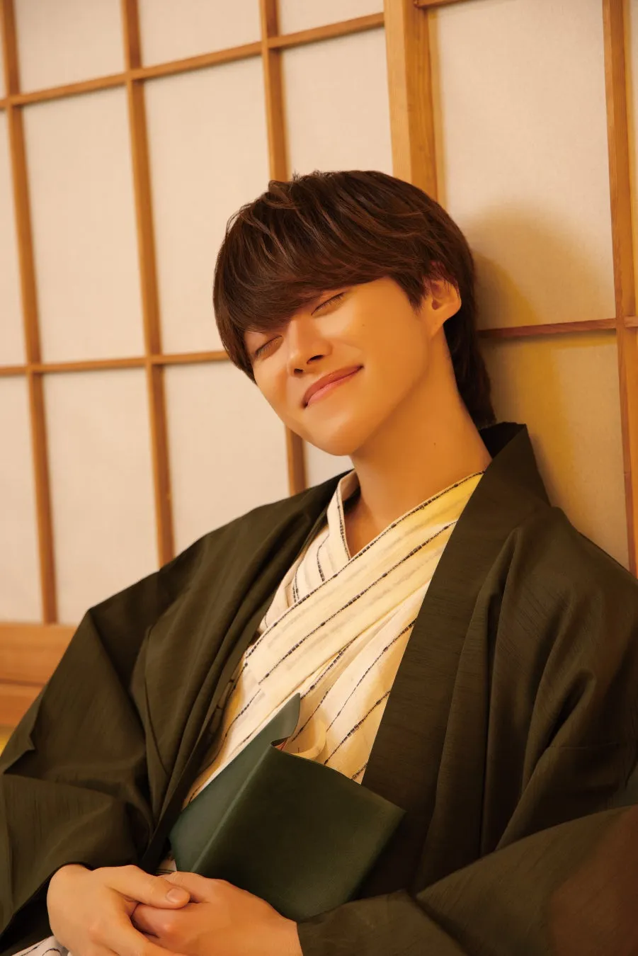 着物を着た男性が目を閉じて微笑んでいる写真です。背景には障子のようなものがあります。