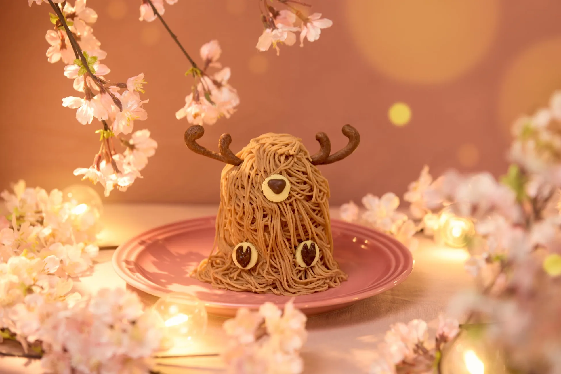 桜の飾りと、トナカイの形をしたモンブランケーキがピンクの皿に載っている写真です。