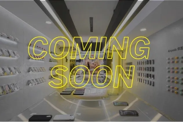 携帯電話のケースやAirpodsなどが販売されている店の内観で、黄色いネオン文字で「COMING SOON」と書かれています。