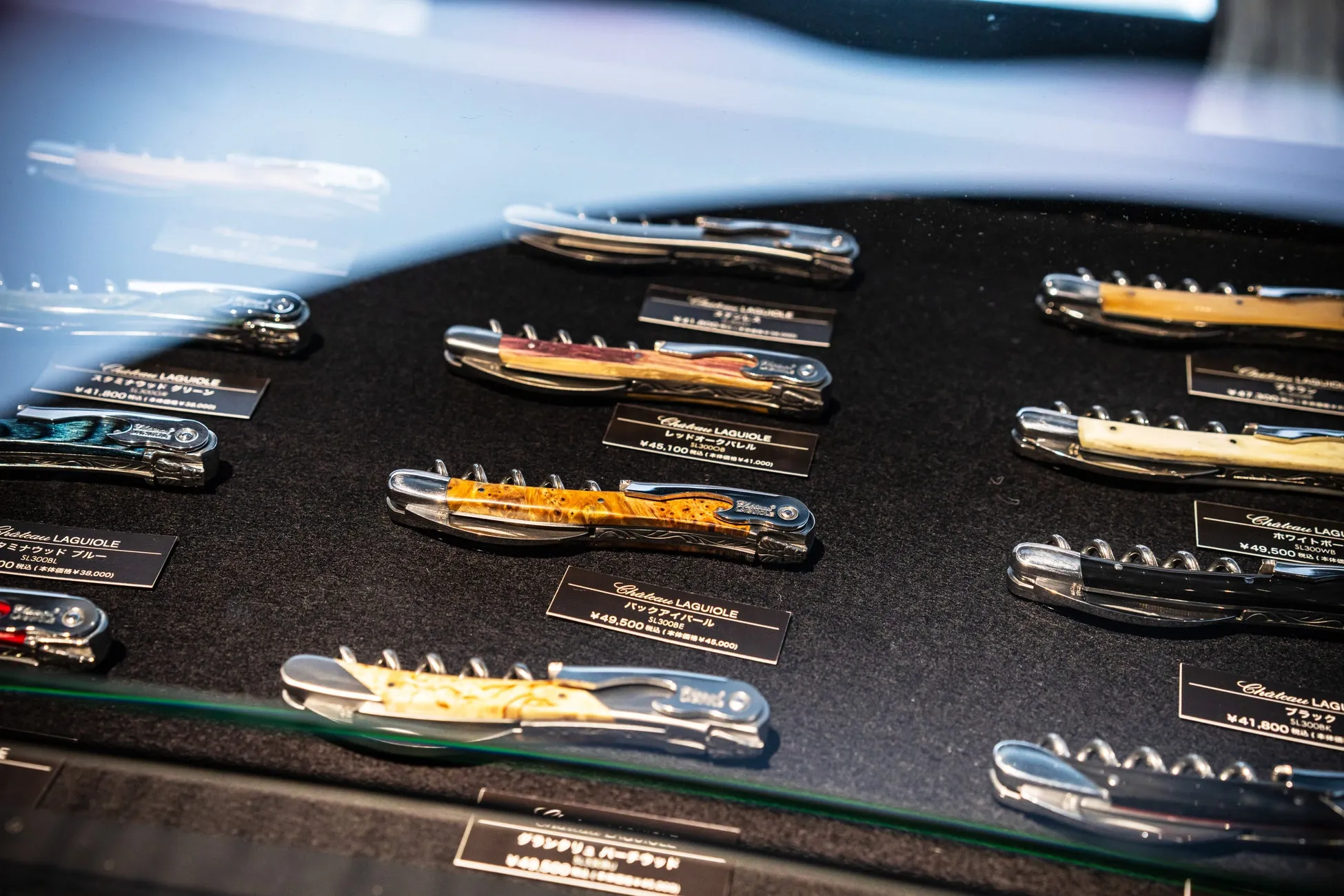 ショーケースに陳列された、様々なデザインのソムリエナイフの写真。木目調や、色とりどりの柄が特徴的。