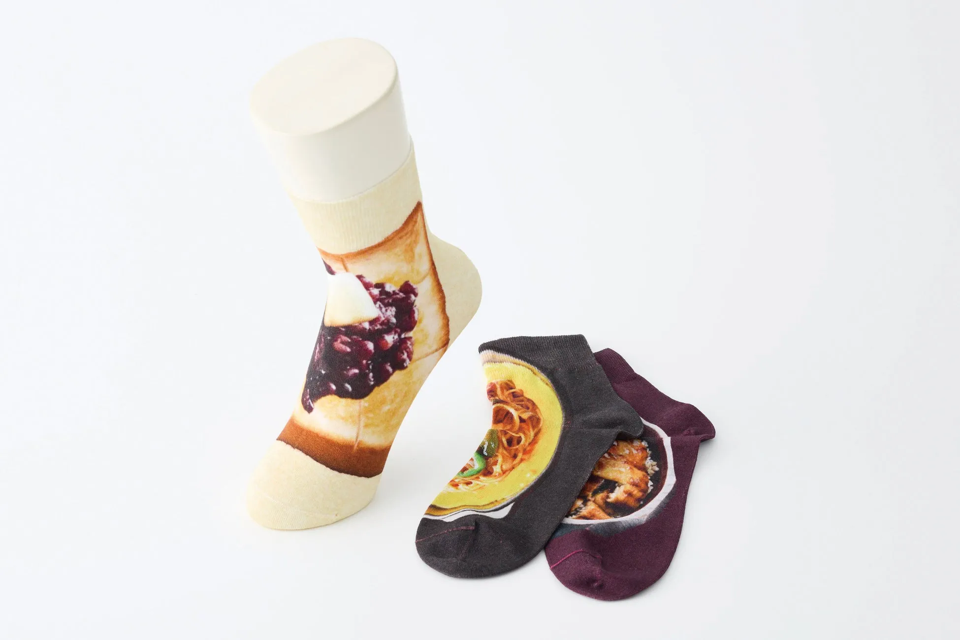 白い背景に、トースト、パスタ、ご飯のイラストが描かれた靴下とマネキンの写真