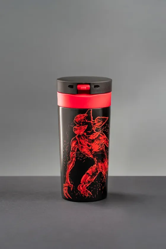 黒いタンブラー。赤いイラストが描かれており、黒い蓋と赤いアクセントが付いている。