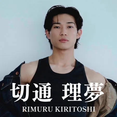 黒いタンクトップを着た男性のポートレート。男性の肩にはデニムジャケットがかけられており、背景は単色。