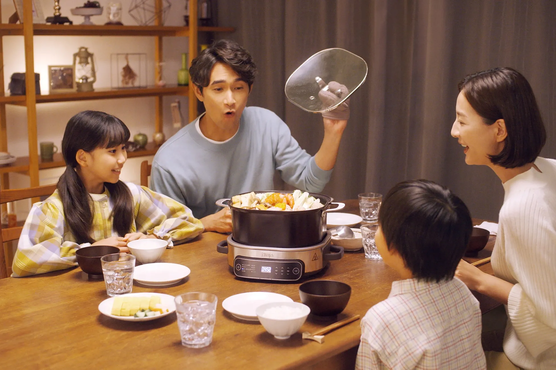 家族が食卓を囲み、鍋料理を楽しんでいる様子