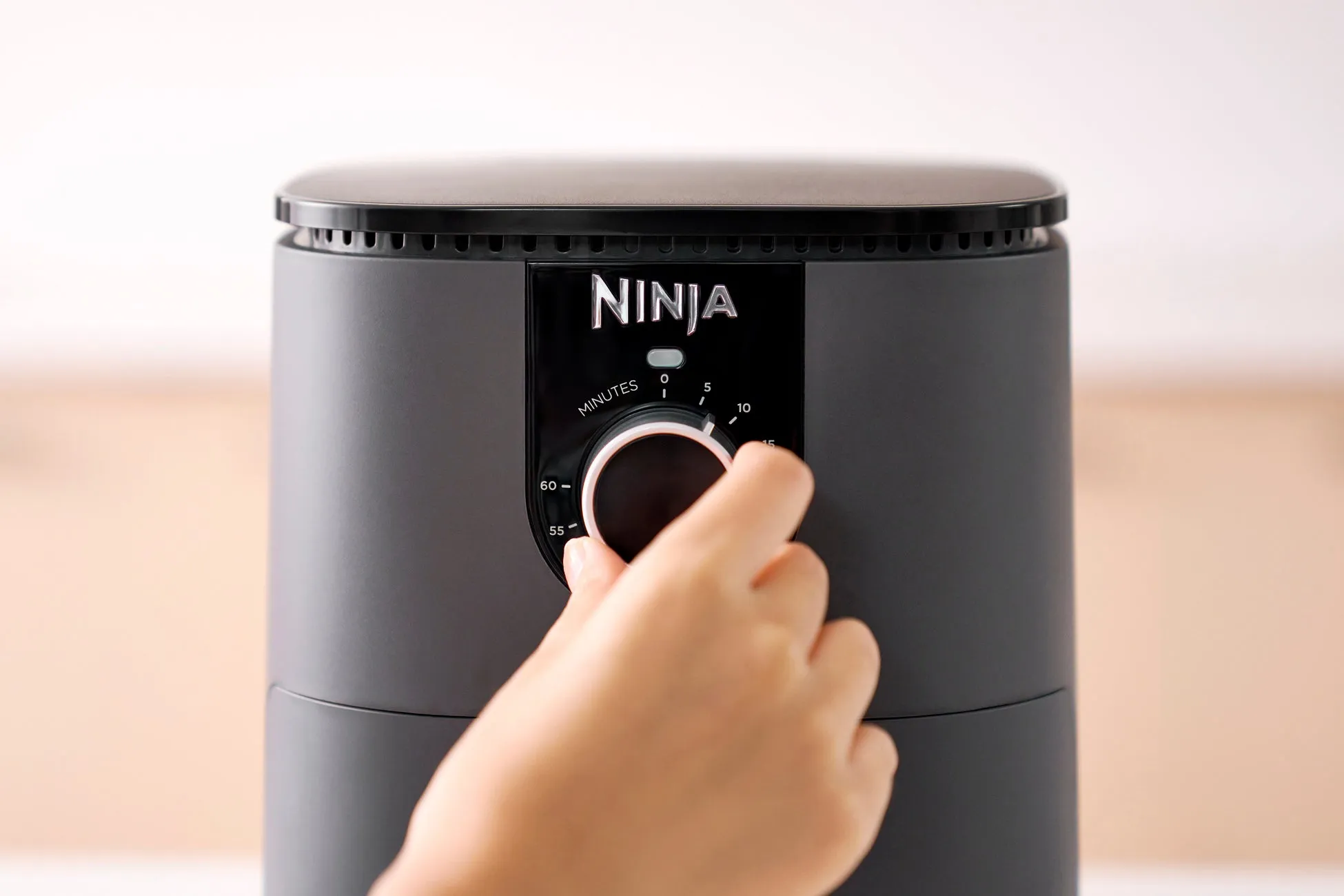 Ninjaのエアフライヤーのクローズアップ画像。エアフライヤーのタイマーを回す手が写っています。