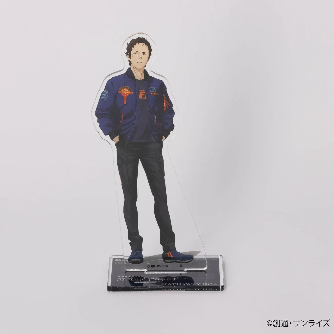 キャラクターのアクリルスタンド。濃い色のジャケットとパンツを着用し、両手をポケットに入れている男性