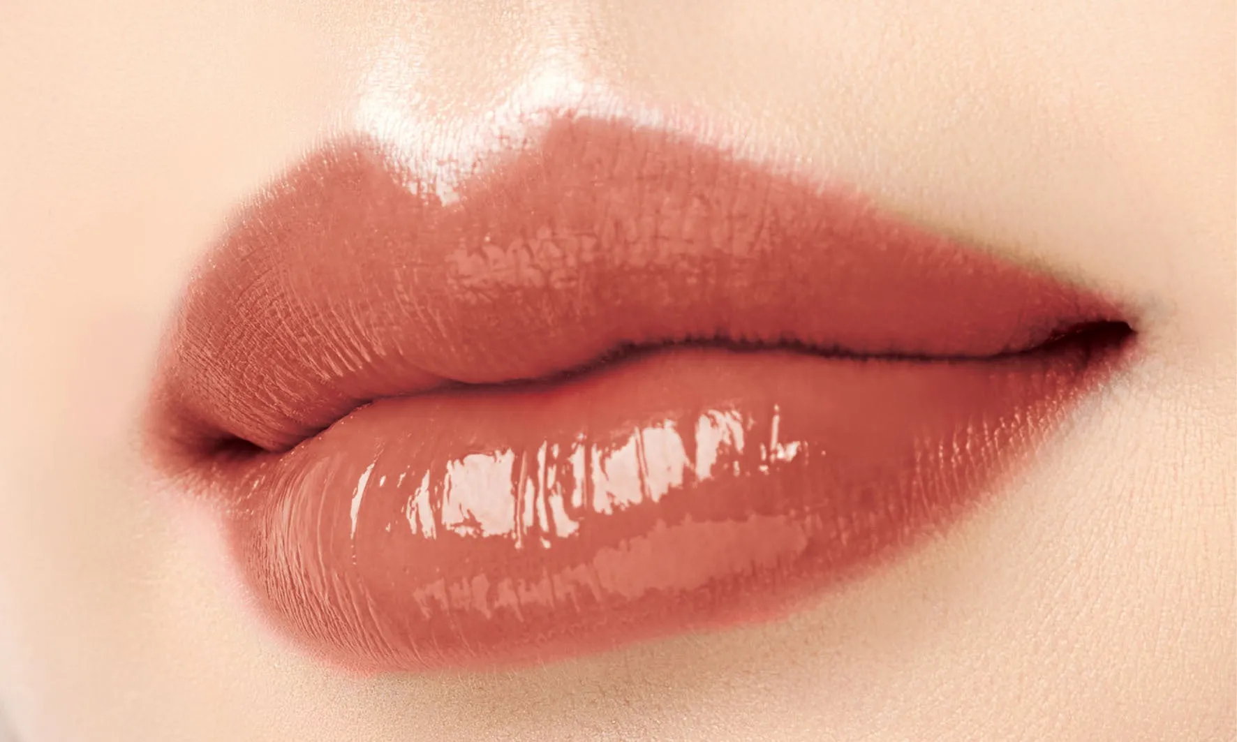 唇のアップ。ベージュ系のリップグロスが塗られており、ツヤのある仕上がりになっている。肌の質感も見える。