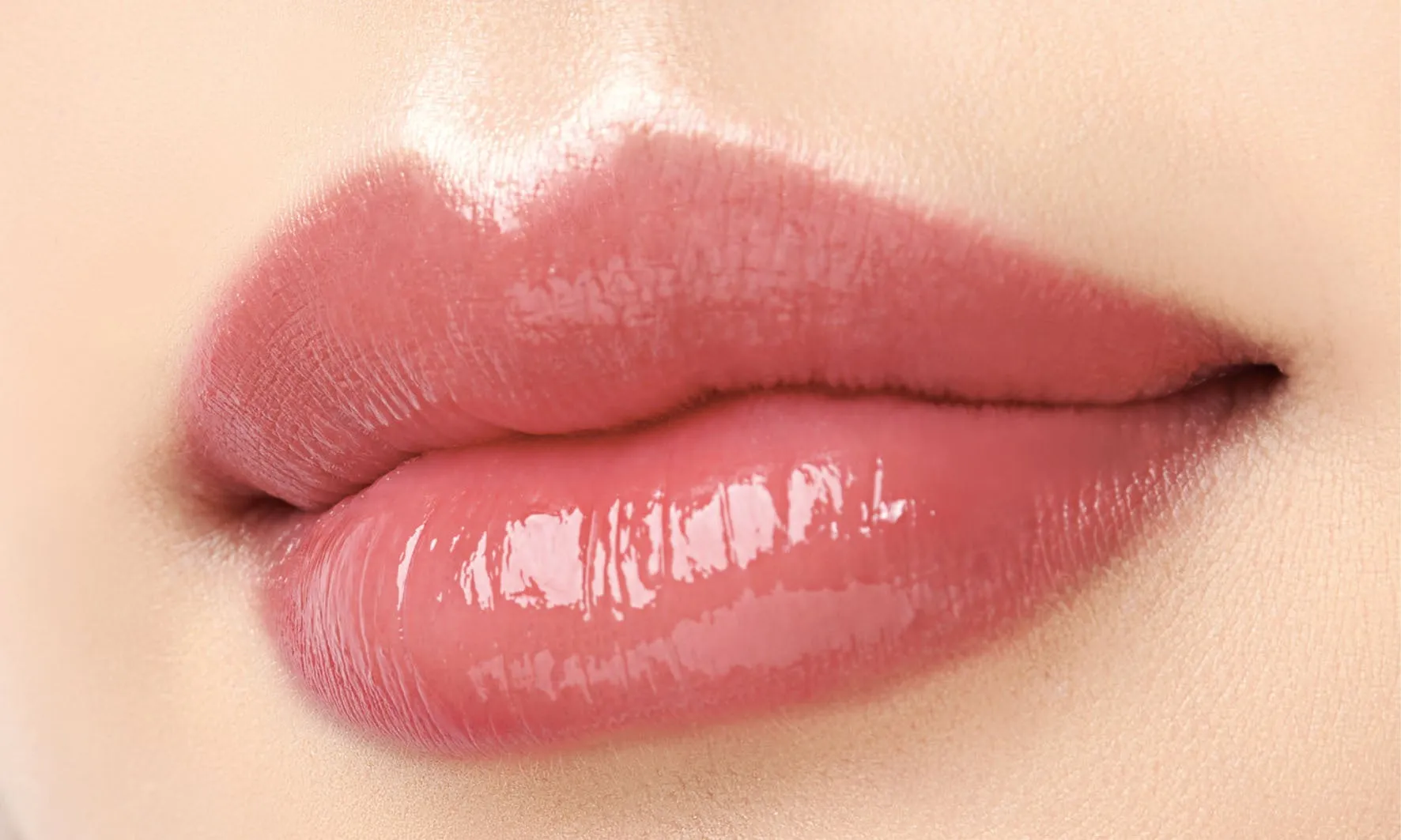 唇のアップ。艶のあるピンク色のリップグロスが塗られている。