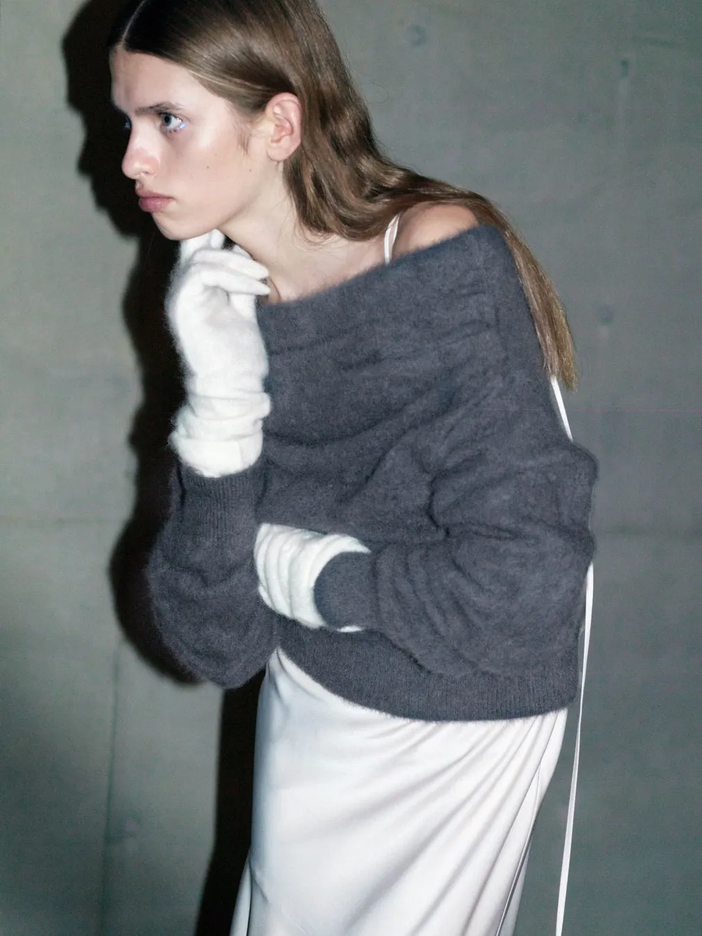 白い手袋とオフショルダーのセーターを着た女性のモノクロ写真