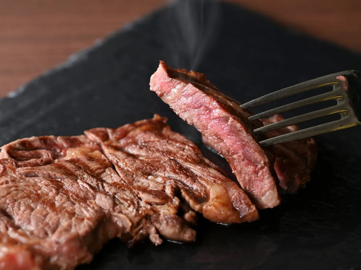 ステーキがフォークで持ち上げられている様子