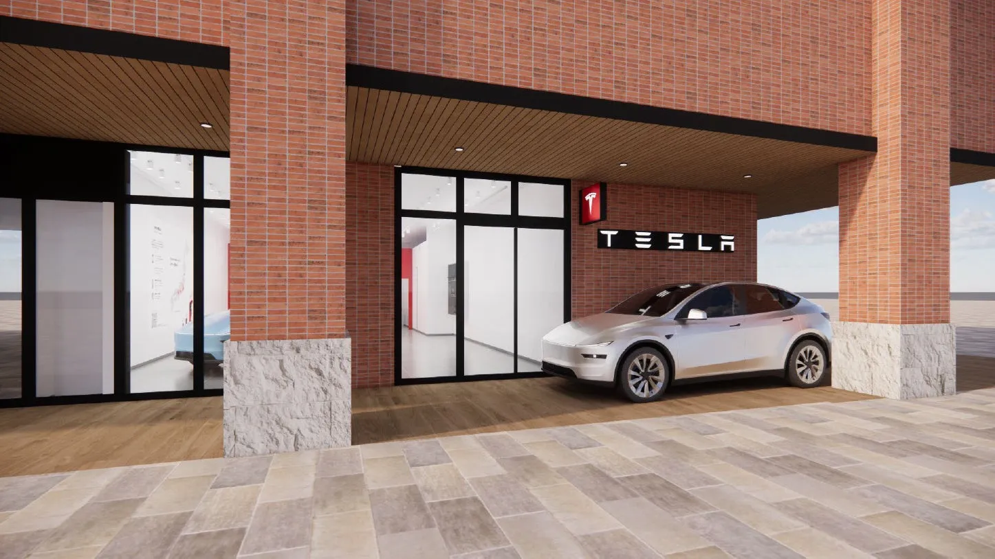 テスラのショールームの外観。白いテスラ車が展示されており、ブランドロゴが壁に表示されている。