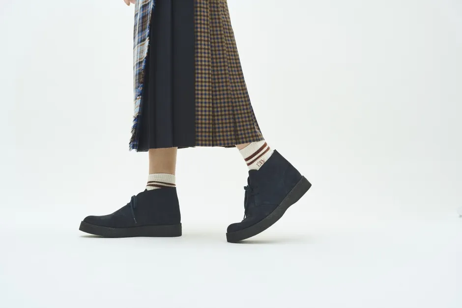 チェック柄のスカートと紺色のデザートブーツを履いた女性の足元の写真です。靴下には「LDY」の文字が見えます。