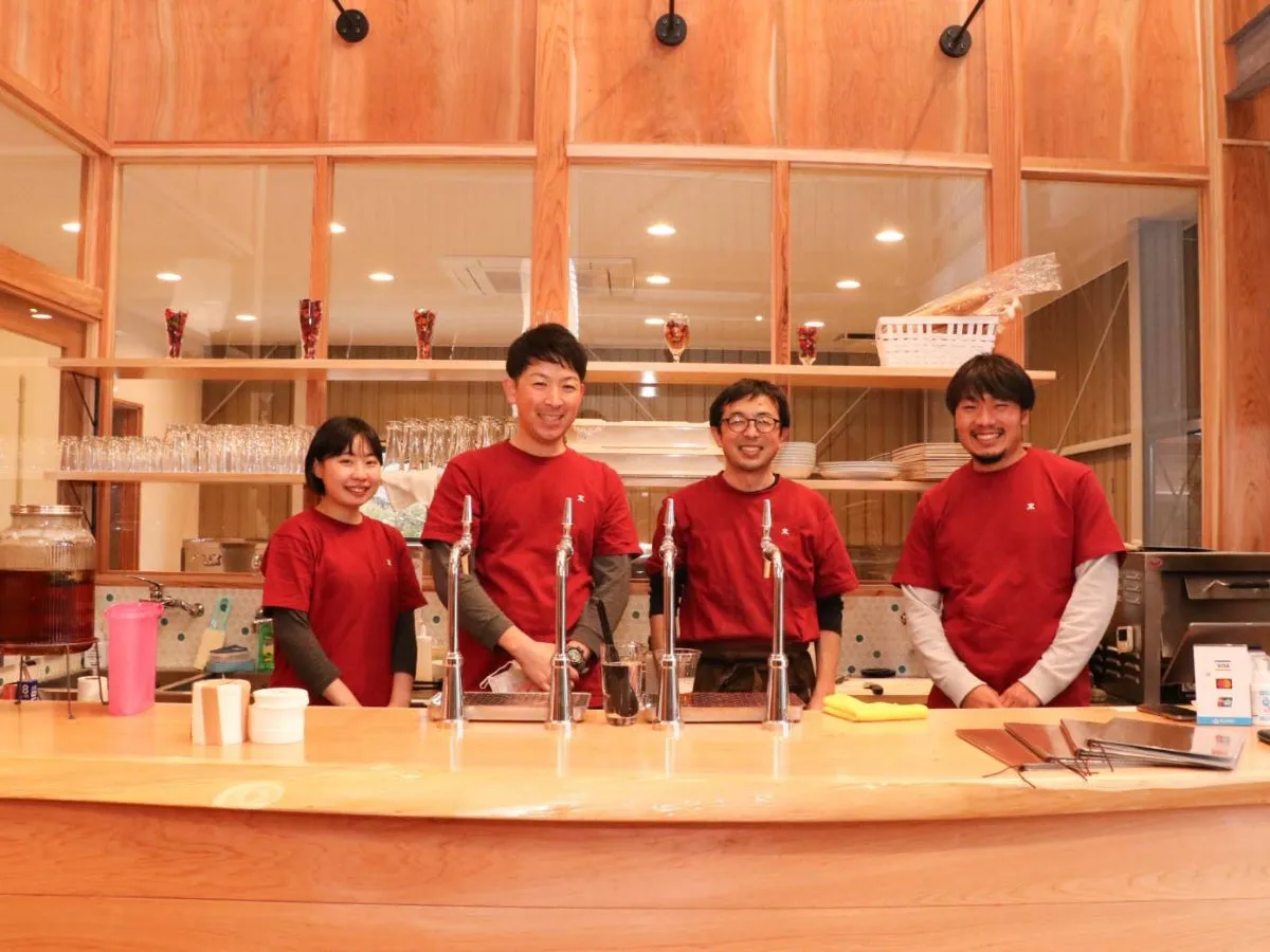 お店のカウンター越しに笑顔で立っている4人の店員の写真。