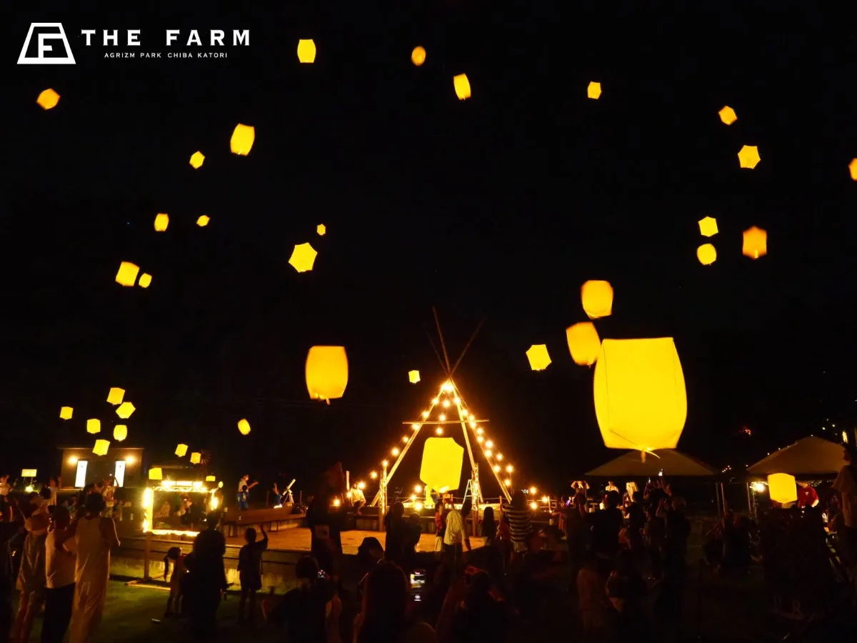 夜空に浮かぶランタンと人々を描いた写真。ランタンは黄色く輝き、イベントの賑わいを象徴している。