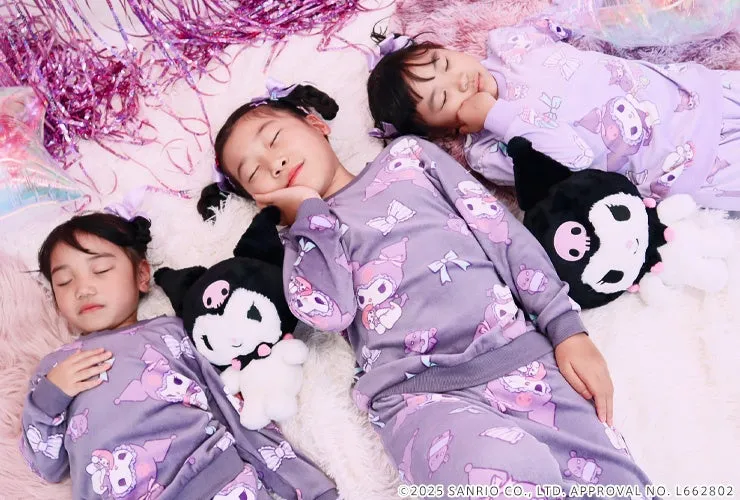 3人の女の子が、クロミのぬいぐるみと一緒に同じパジャマを着て、毛布の上で寝ている写真です。