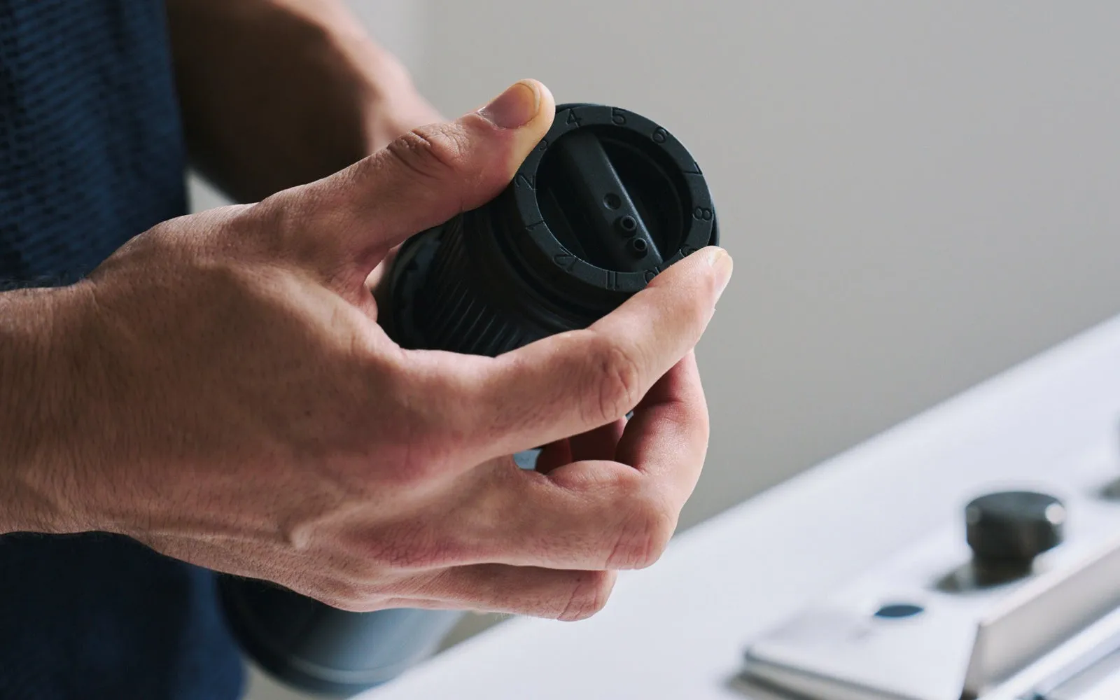 黒い円筒形の物体を両手で持っている人のクローズアップ写真