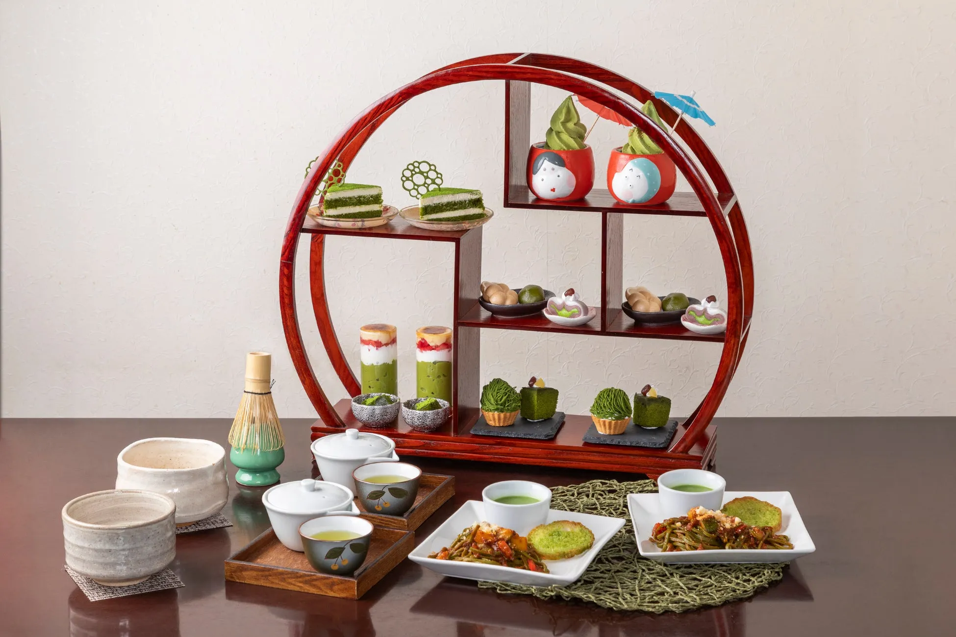 和風のアフタヌーンティーセットの画像。三段の木製のスタンドには、抹茶ケーキ、抹茶ソフトクリーム、デザートが並び、テーブルには抹茶そば、抹茶ドリンク、抹茶スイーツが配置されている。