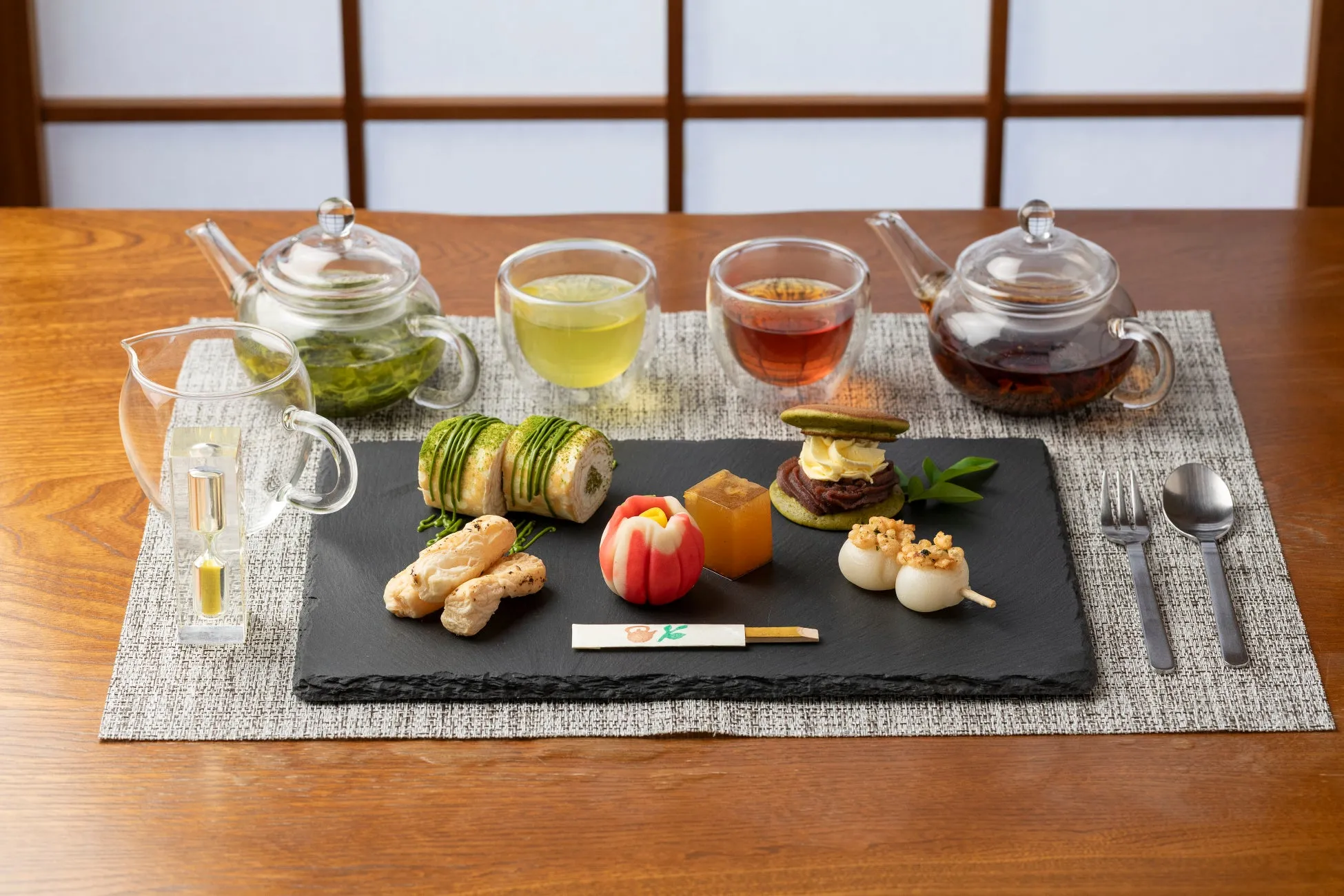 様々なお菓子と飲み物が並んだ写真。お茶、お菓子、茶器、カトラリーがセットでテーブルに置かれている。
