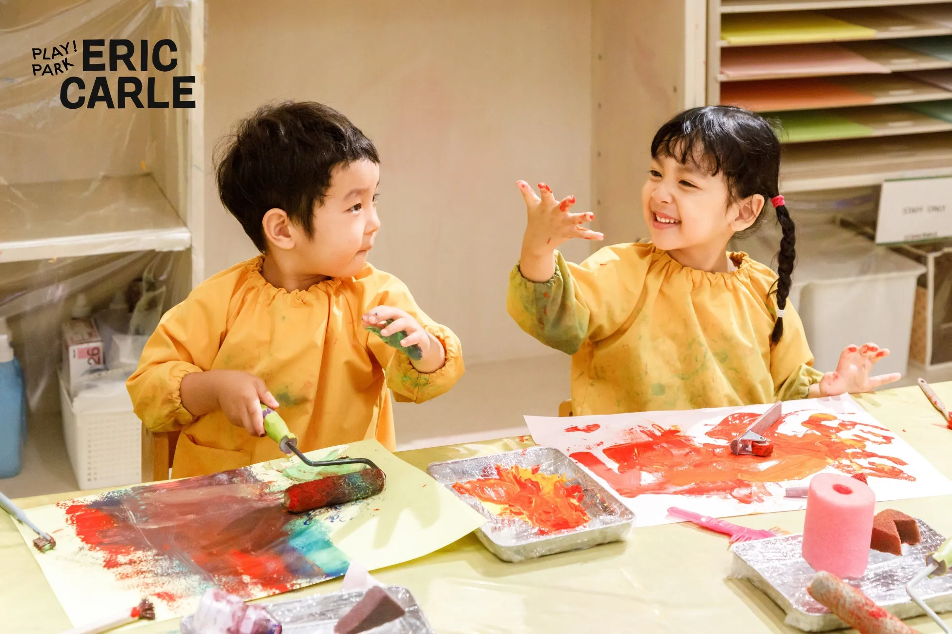 2人の子供が絵の具を使って楽しそうに遊んでいる様子。