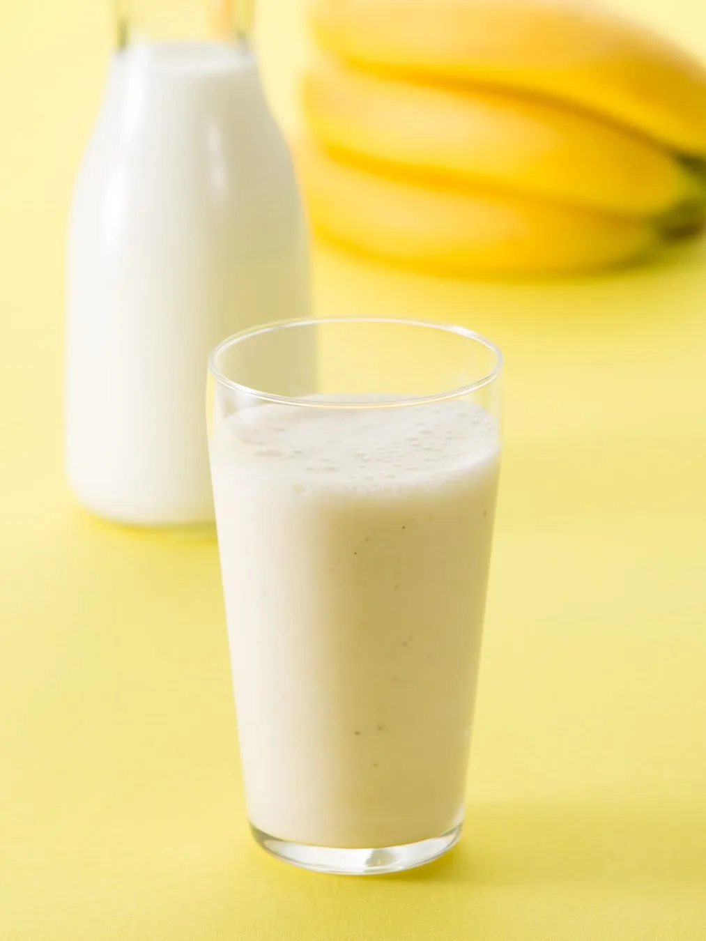 バナナ、牛乳、バナナシェイク、ガラスのコップが写った写真。