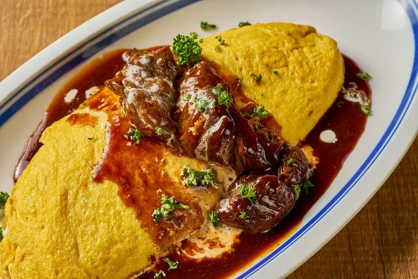 オムライスの上にデミグラスソースのかかった牛肉