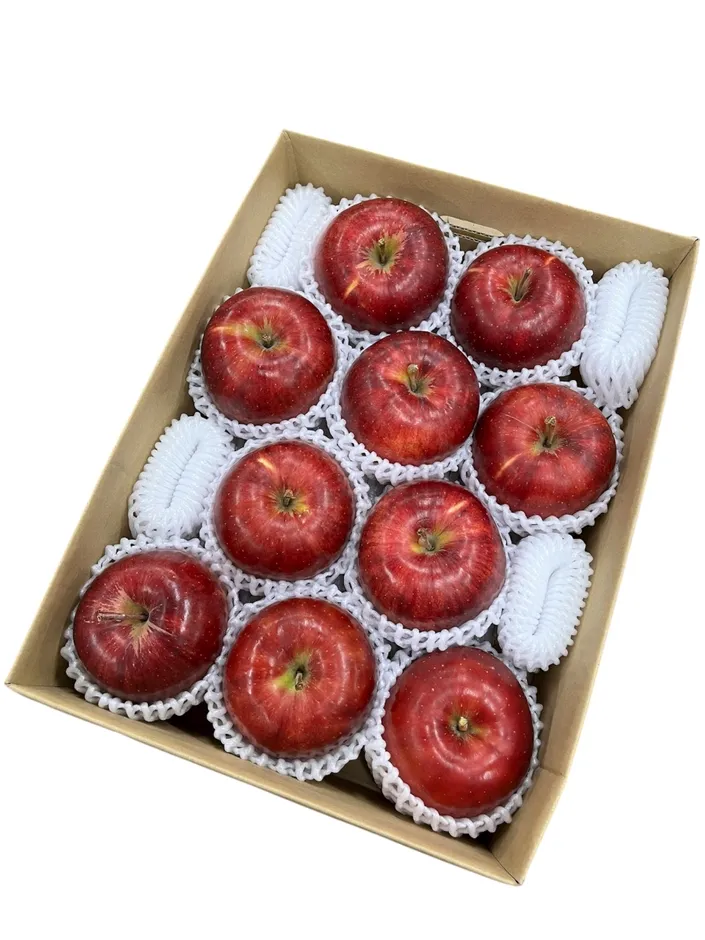 赤いリンゴが10個、保護材に包まれて段ボール箱に入っている様子。
