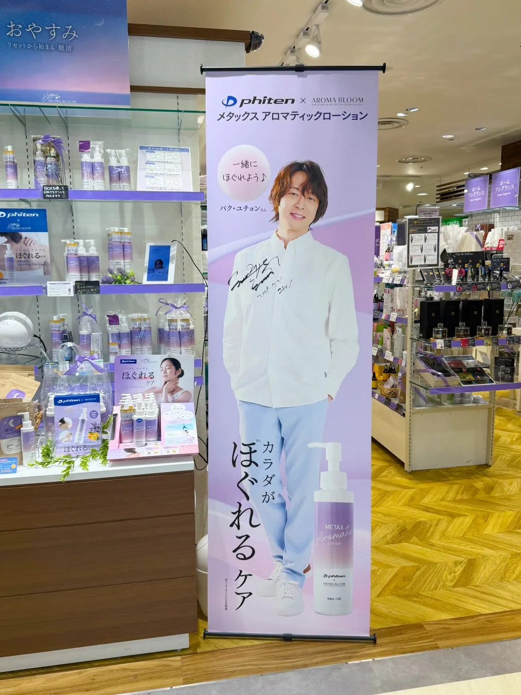店内にあるPhitenとAROMA BLOOMのコラボ商品の広告。モデルはパク・ユチョンさんで、メタックスアロマティックローションの宣伝をしている。商品は棚に並べられ、販促物も設置されている。