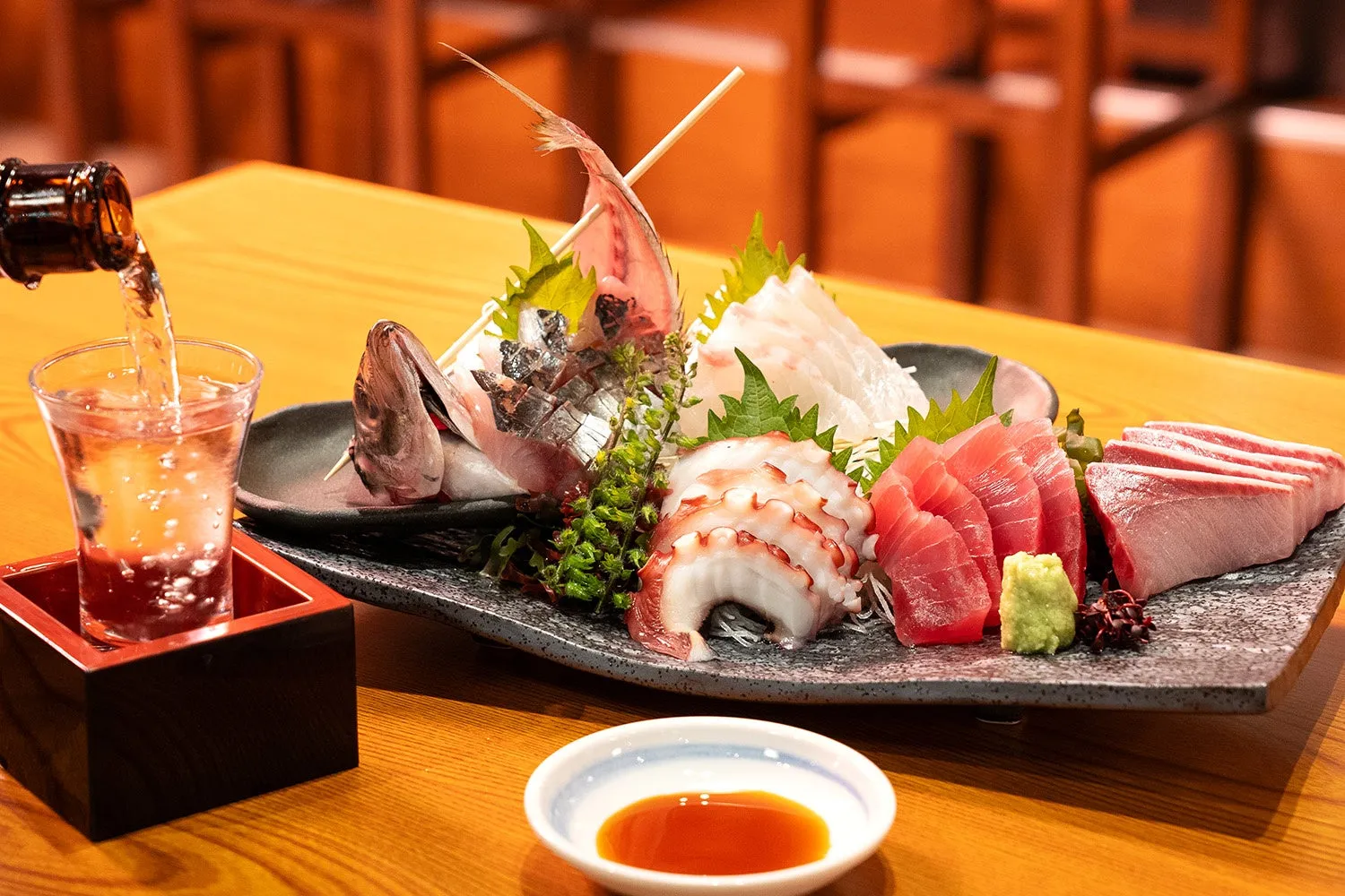 お刺身の盛り合わせと日本酒のショットグラスが写っている写真です。