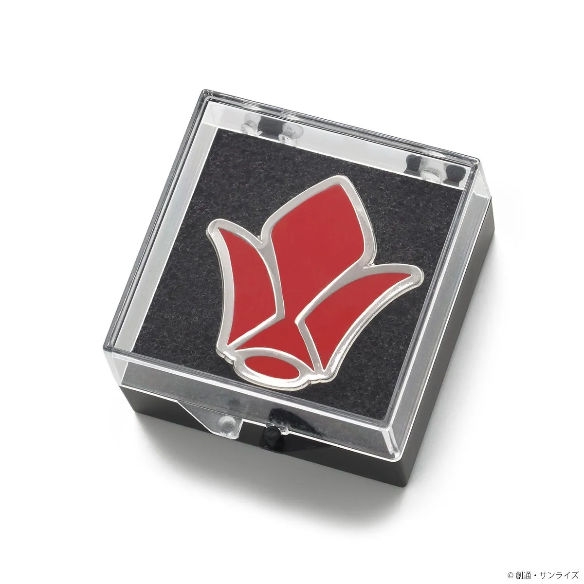 赤い花の形をしたバッジが、黒い台座の上に透明なケースに入っている様子を写した画像です。バッジは銀色の縁取りがあり、ケースは光を反射しています。