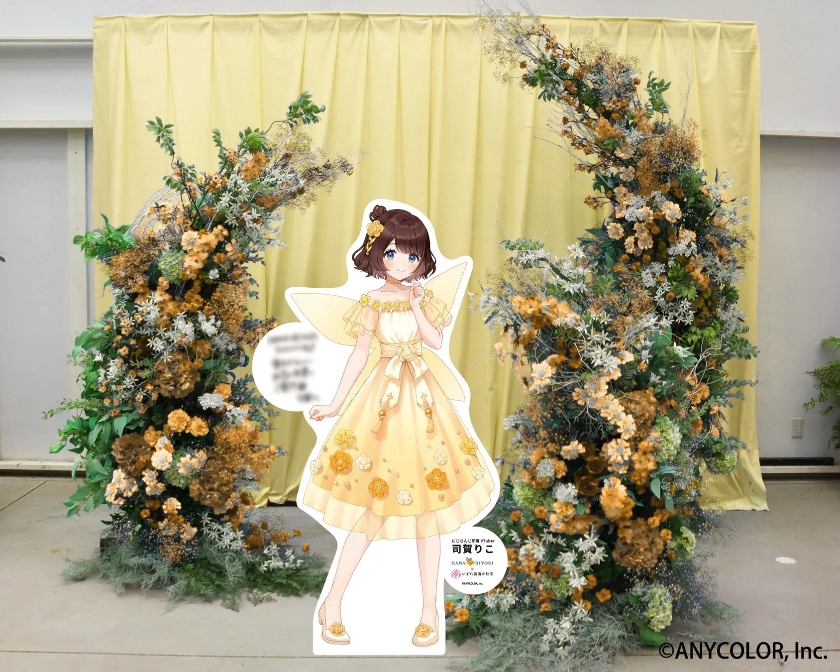 司賀りこの等身大パネルが花で飾られたアーチの前に立っている。